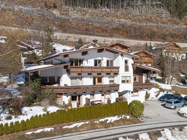 Un hôtel à plusieurs étages doté de balcons, avec un télésiège visible au loin et un paysage enneigé.