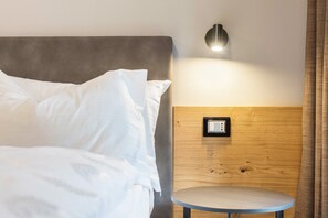 Una habitación de hotel con cama, una mesa redonda, una lámpara de pared y un enchufe.