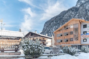 Un edificio con un cartel que dice 'Residence Kamarlo Restaurant Pizzeria', fachada de madera y un telón de fondo montañoso.