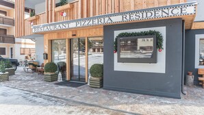 A restaurant named 'Pizzeria Residence' with a wooden facade, glass doors, and outdoor seating.