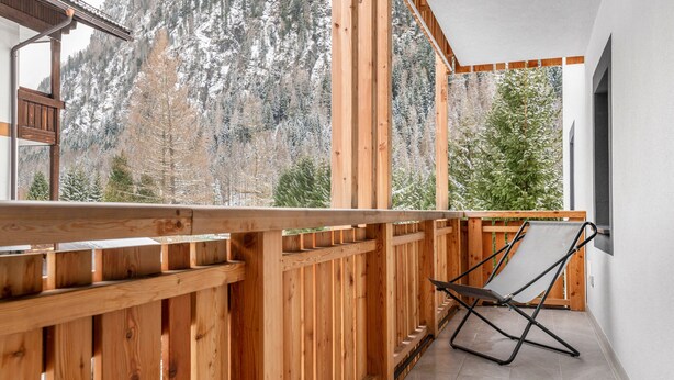 A wooden balcony with a view of a forested mountain.