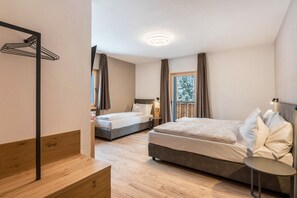 A hotel room with two beds, a wooden bench, a small table, and a view of the outdoors. - Kamerloy Apartments - D with Mountain View, Wi-Fi, Balcony and Garden (Campitello di Fassa)