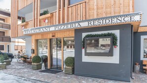 Ein Restaurant namens 'Pizzeria Residence' mit Holzfassade, Außenbestuhlung und einem gerahmten Bild an der Wand.