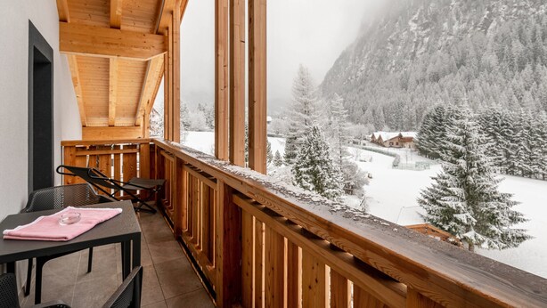A wooden balcony with a view of a snowy landscape and mountains. - Kamerloy Apartments - F with Mountain View, Wi-Fi, Balcony and Garden (Campitello di Fassa)
