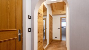 A hallway with wooden flooring, a wooden door, and a white wall with a framed picture. - Kamerloy Apartments - F with Mountain View, Wi-Fi, Balcony and Garden (Campitello di Fassa)