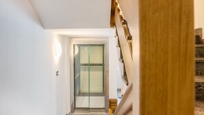 A modern interior with a glass elevator, a wooden staircase, and a clean, white wall. - Kamerloy Apartments - F with Mountain View, Wi-Fi, Balcony and Garden (Campitello di Fassa)