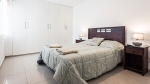 Ein Schlafzimmer mit Bett, Nachttischen, einem Kleiderschrank und einer Lampe.