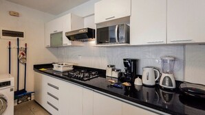 Eine moderne Küche mit weißen Schränken, einer schwarzen Arbeitsplatte, einer Mikrowelle, einer Kaffeemaschine und einem Mixer.