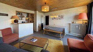 A modern hotel room with a wooden ceiling, a dining area, a bed, and a reception desk. - Résidence de l'Oisans 4 rooms - Quartier Cognet (Alpe d'Huez)