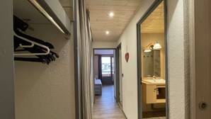 Ein Flur mit Holzboden, der zu einem Badezimmer mit Spiegel und Waschbecken führt.