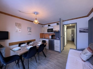 Een kleine leefruimte met een eethoek, kitchenette en een zithoek.