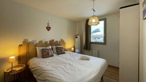 Ein Schlafzimmer mit einem großen Bett, einer Nachttischlampe, einem Fenster mit Aussicht und einer Deckenleuchte.