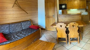 A cozy room with a wooden sofa, a small dining table, and wooden chairs. - 3-room Apt Les Saisies, 6 ppl, Pets allowed (Les Saisies)