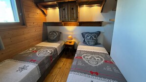 A small, cozy room with two beds, wooden walls, a window, and a ceiling lamp. - 3-room Apt Les Saisies, 6 ppl, Pets allowed (Les Saisies)