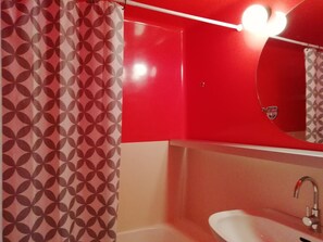 A bathroom with a red and beige color scheme, a white sink, and a mirror with a red frame. - Bright studio for 4 in Arc 2000 center (Les Arcs 2000)