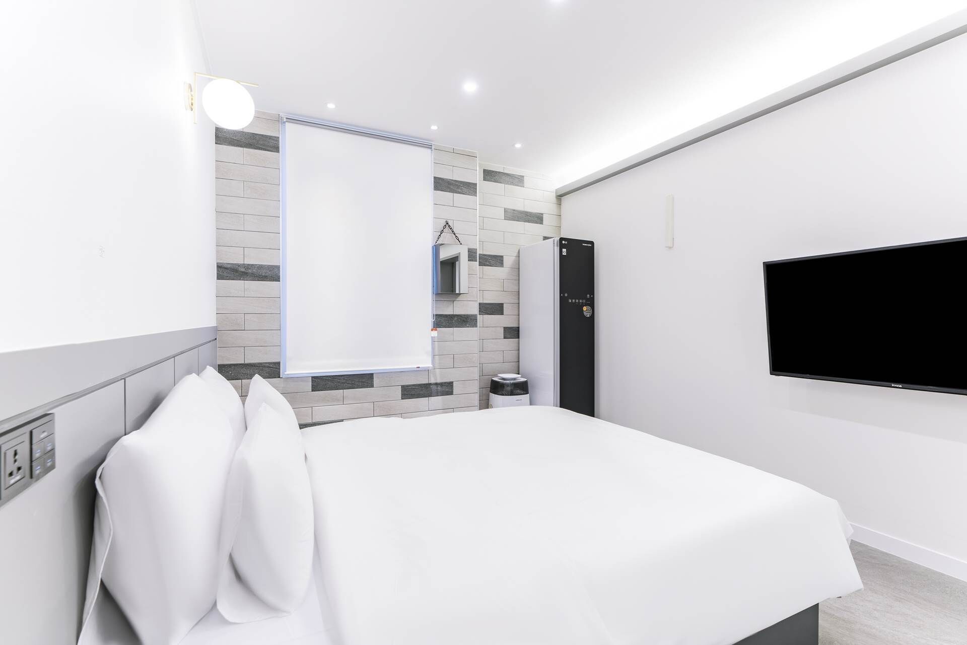 Una habitación de hotel moderna con cama, televisor, calentador y una pequeña mesa.