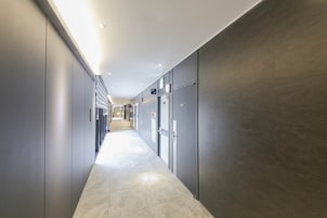 Um corredor moderno com armários, piso ladrilhado e teto com iluminação embutida.