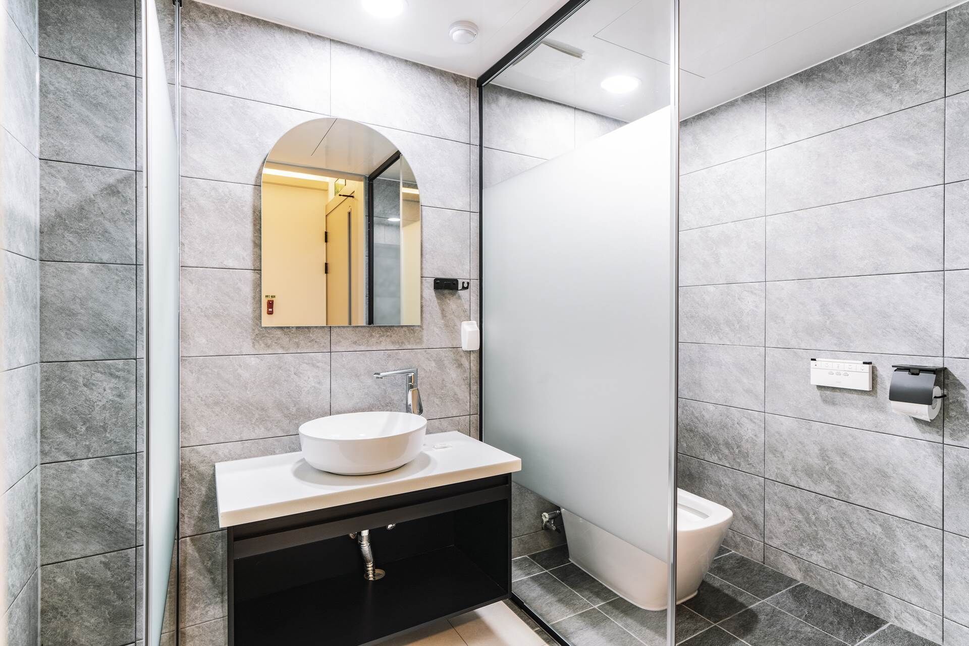 Un baño moderno con un lavamanos blanco, un espejo y un inodoro.