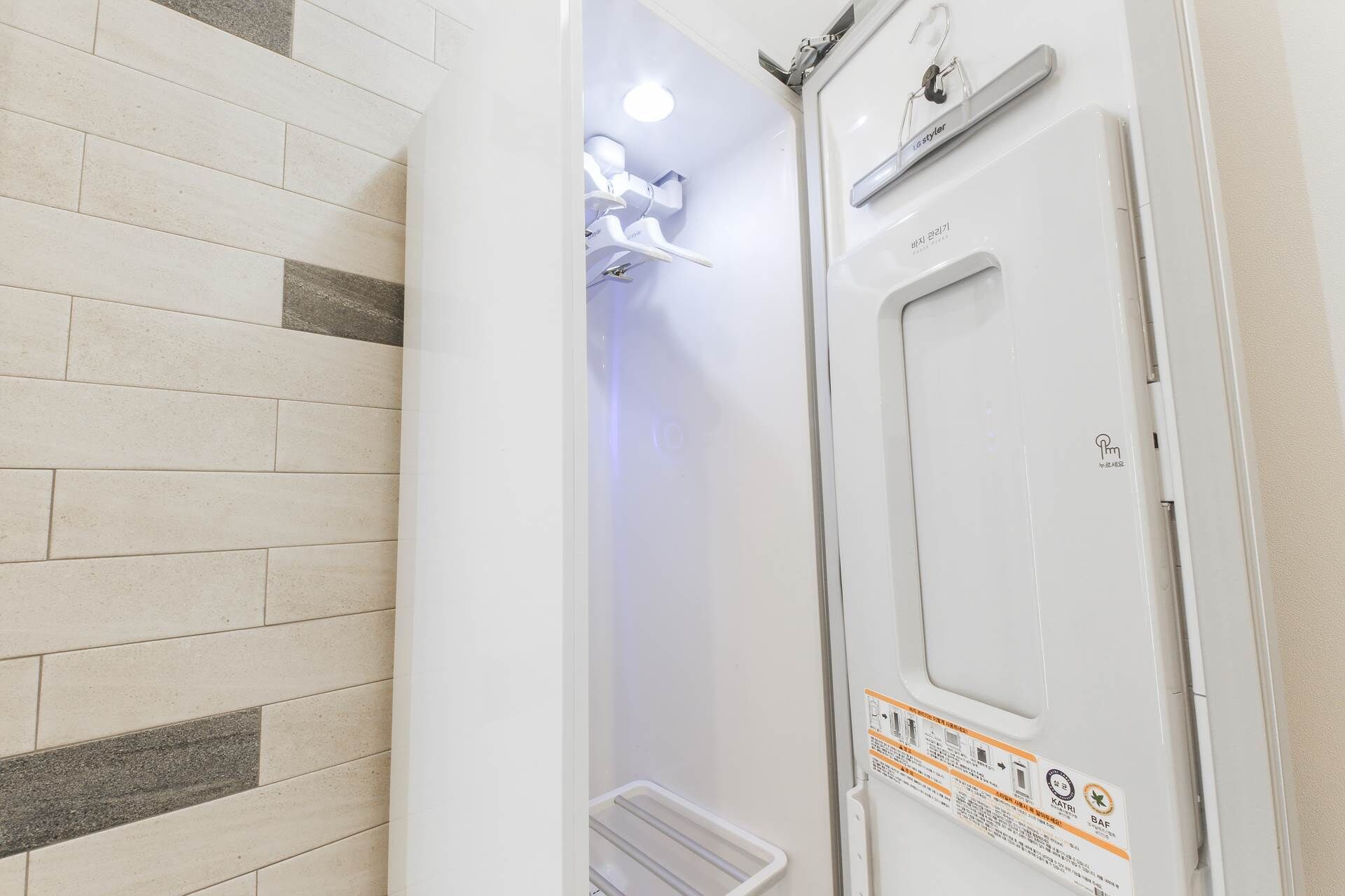 Un baño con una puerta blanca, un perchero y una zona de ducha.