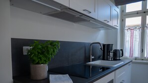 A modern kitchen with a black countertop, a built-in oven, and a window with curtains. - Holiday apartment Käte (ferienwohnungen1886) (Borsdorf)