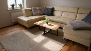A living room with a beige sofa, a wooden coffee table with a plant, and a painting on the wall. - Holiday apartment Käte (ferienwohnungen1886) (Borsdorf)