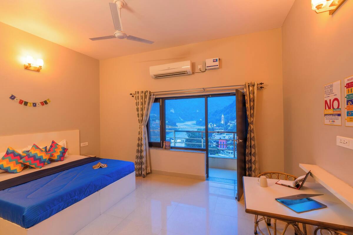 Una habitación de hotel con cama, escritorio y vista a la ciudad.