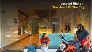 A hotel entrance with a glass facade, a seating area, and a motorcycle parked outside. - goSTOPS Rishikesh, Lakshman Jhula (Yamkeshwar)
