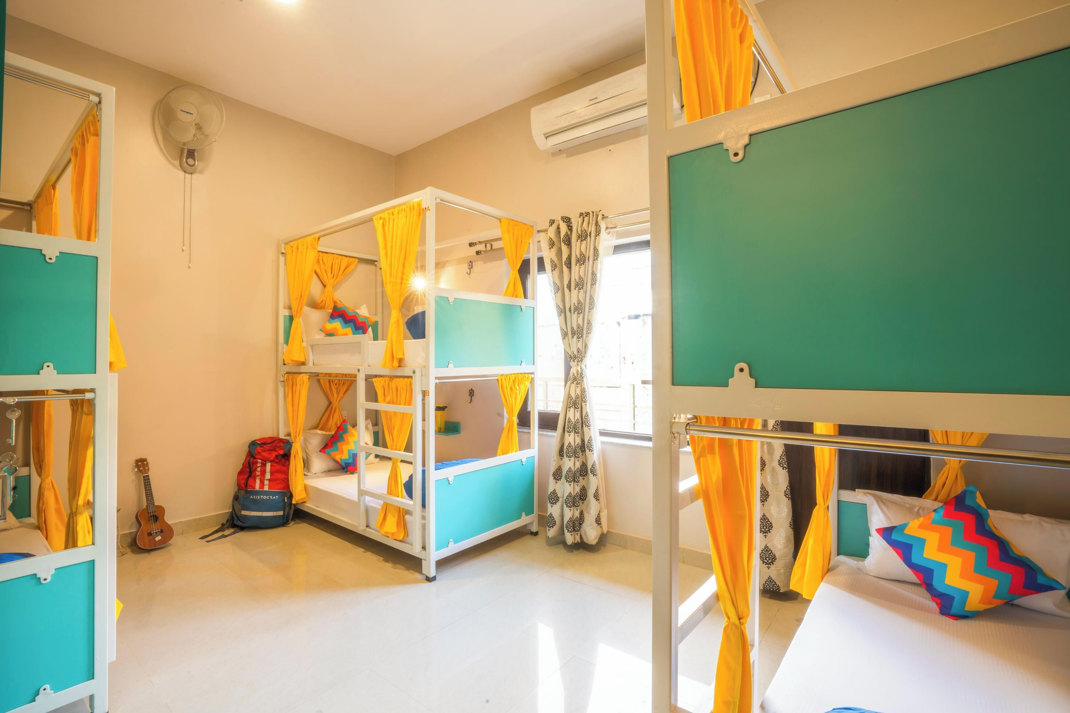 A dormitory room with bunk beds, a guitar, and a backpack on the floor.