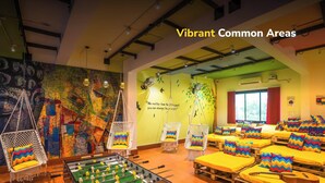 A vibrant common area with hanging chairs, colorful cushions, and a foosball table. - goSTOPS Rishikesh, Lakshman Jhula (Yamkeshwar)