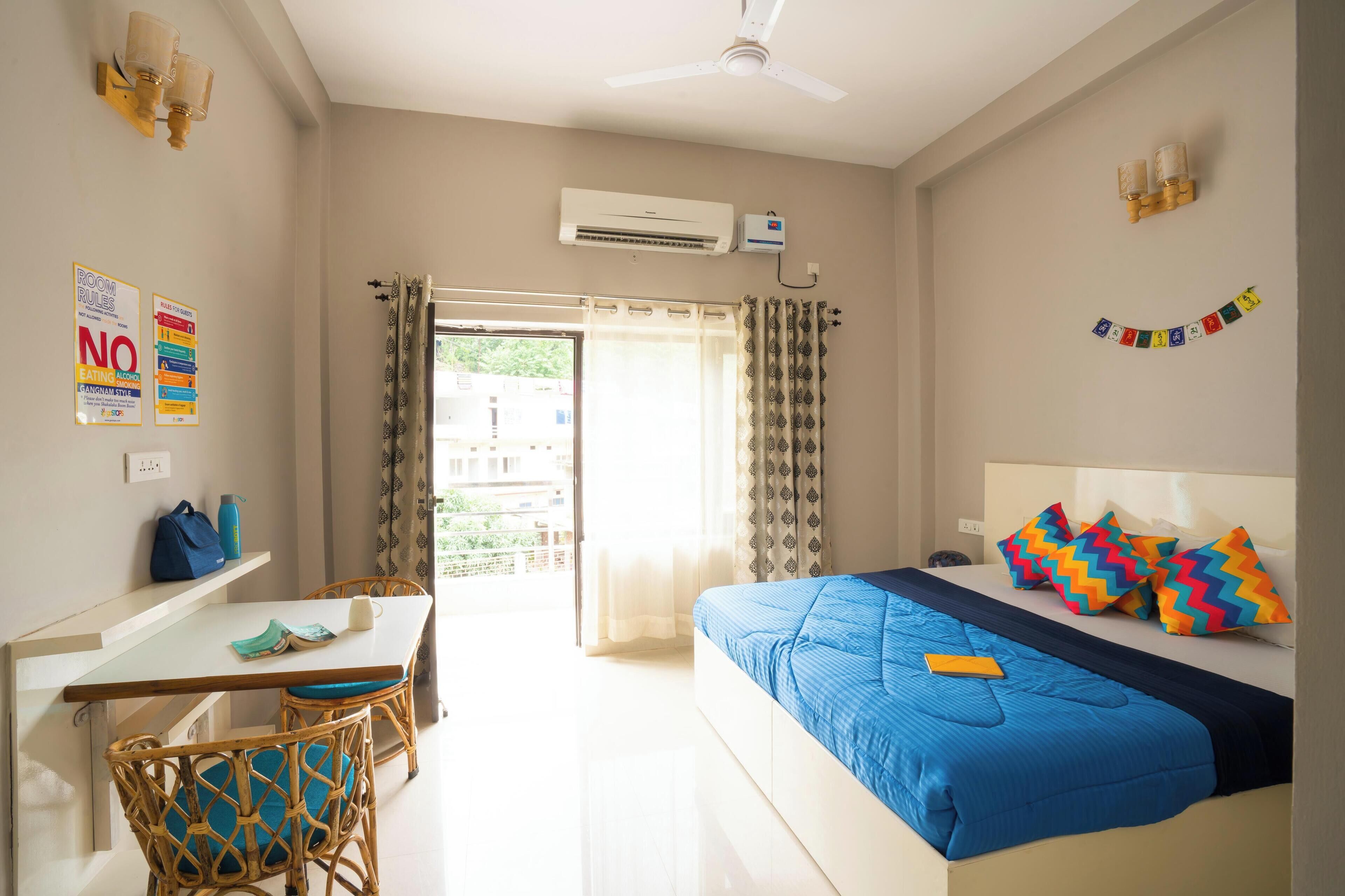 Een hotelkamer met een bed, een bureau, een stoel en een airconditioning.