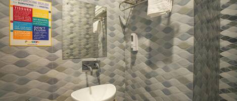 Une salle de bain avec un lavabo blanc, un porte-serviettes et une douche. Un panneau affiche les règles à respecter dans la salle de bain.