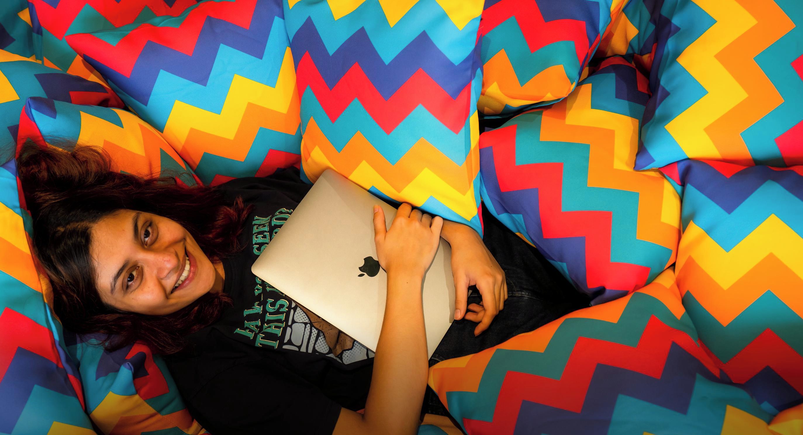 A person lying on a bed with a colorful zigzag patterned blanket.