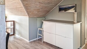 A small, cozy attic bedroom with a sloped ceiling, a white wardrobe, a small chair, and a framed picture on the wall. - 3 bedroom cozy apartment in Mandal (Mandal)