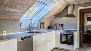 A modern kitchen with a skylight, built-in dishwasher, oven, and a dining area with a bench. - 3 bedroom cozy apartment in Mandal (Mandal)
