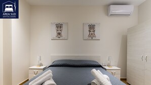 A hotel room with a bed, two nightstands, a wardrobe, and two wall-mounted air conditioners. - South Area Guesthouse (self check-in) (Canicattì)