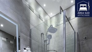 A modern bathroom with a glass-enclosed shower, a sink with a mirror, and tiled walls. - South Area Guesthouse (self check-in) (Canicattì)