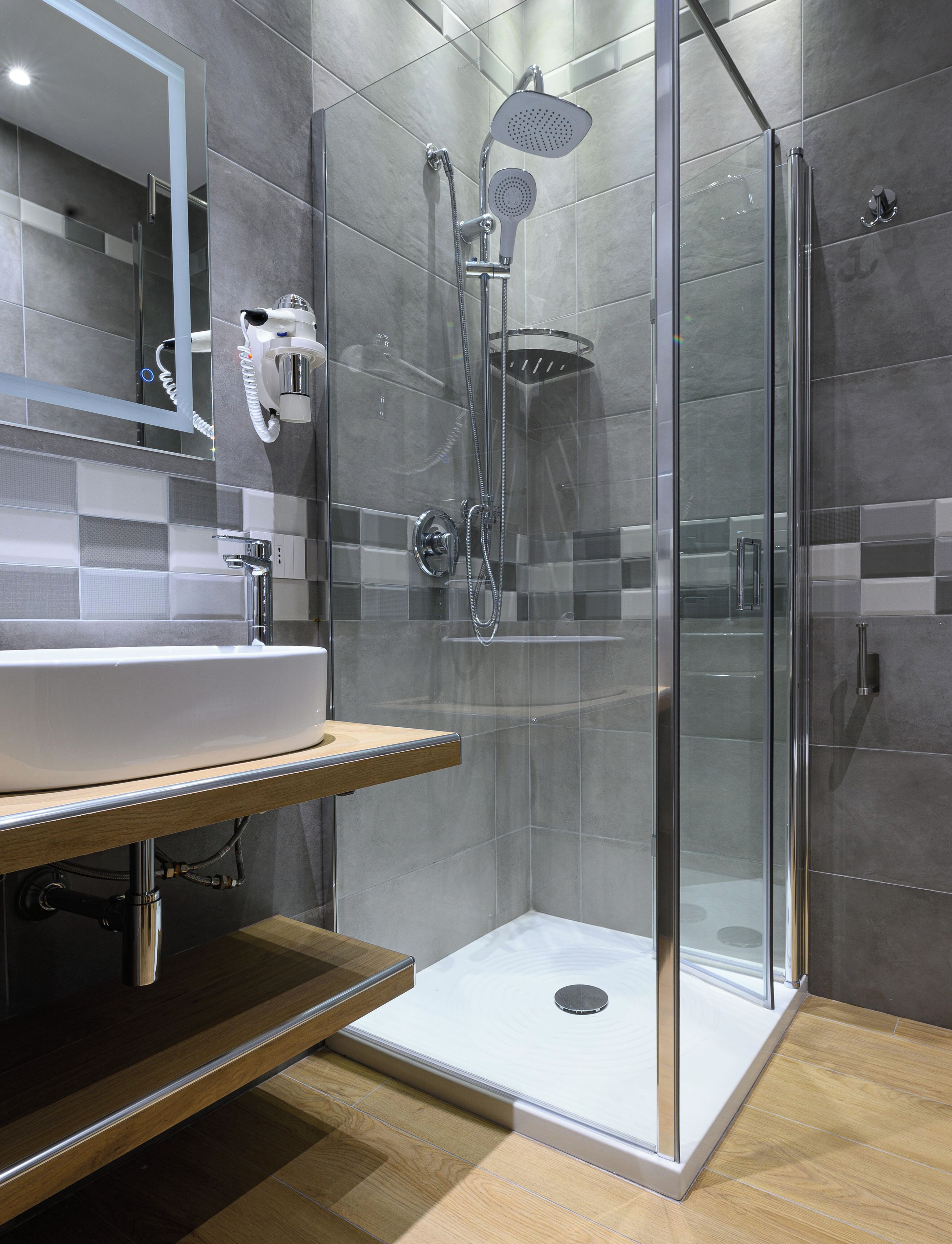 A modern bathroom with a glass-enclosed shower, a sink with a mirror, and tiled walls.