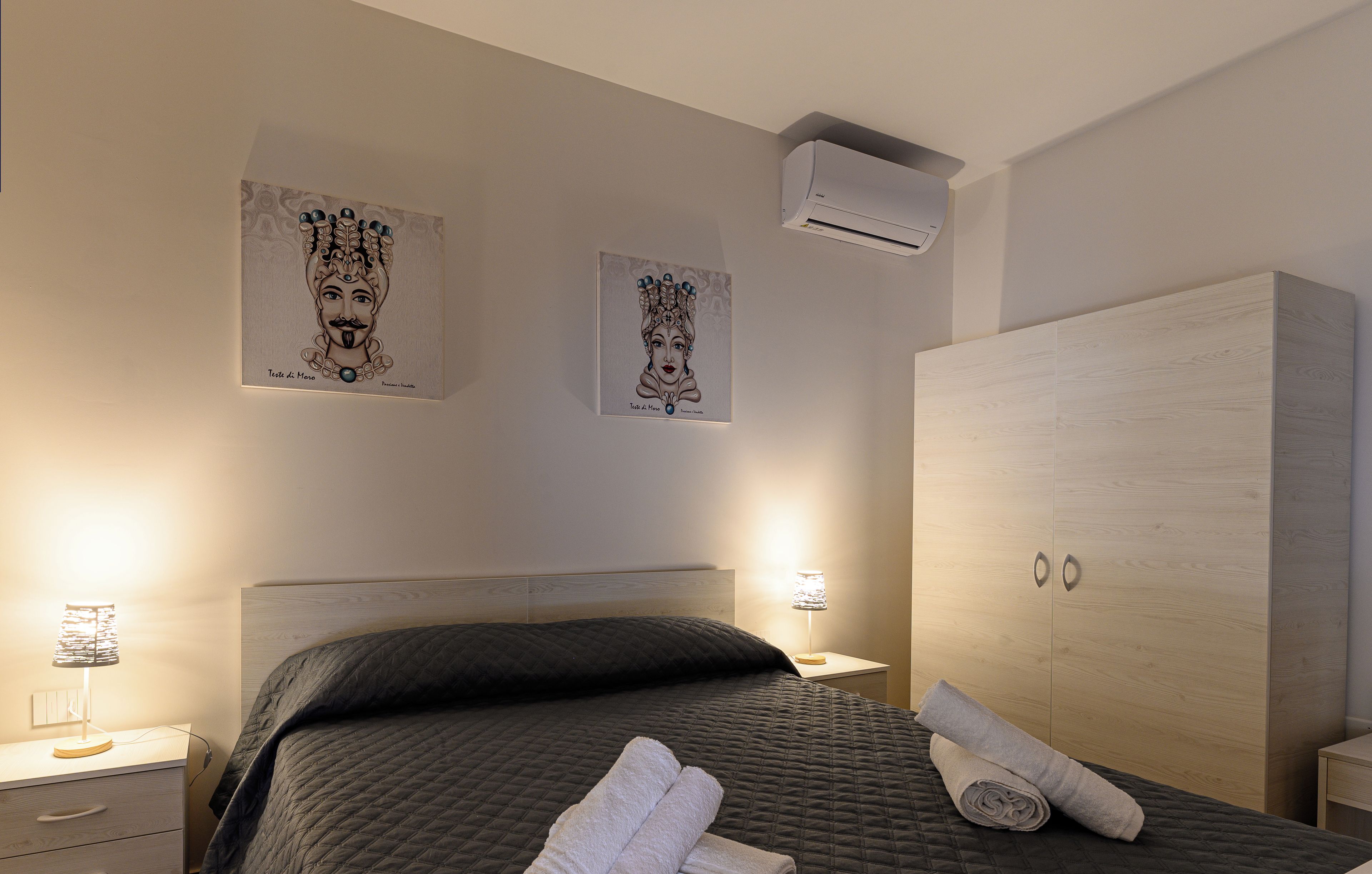 Une chambre d’hôtel avec un lit, une armoire, une table de chevet et des œuvres d’art murales.