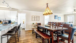 A spacious kitchen with a wooden dining table, bar stools, and a hanging light fixture. - 4 Bedroom 2 Bath Ocean Front Vacation Rental on Edisto Beach (Edisto Beach)