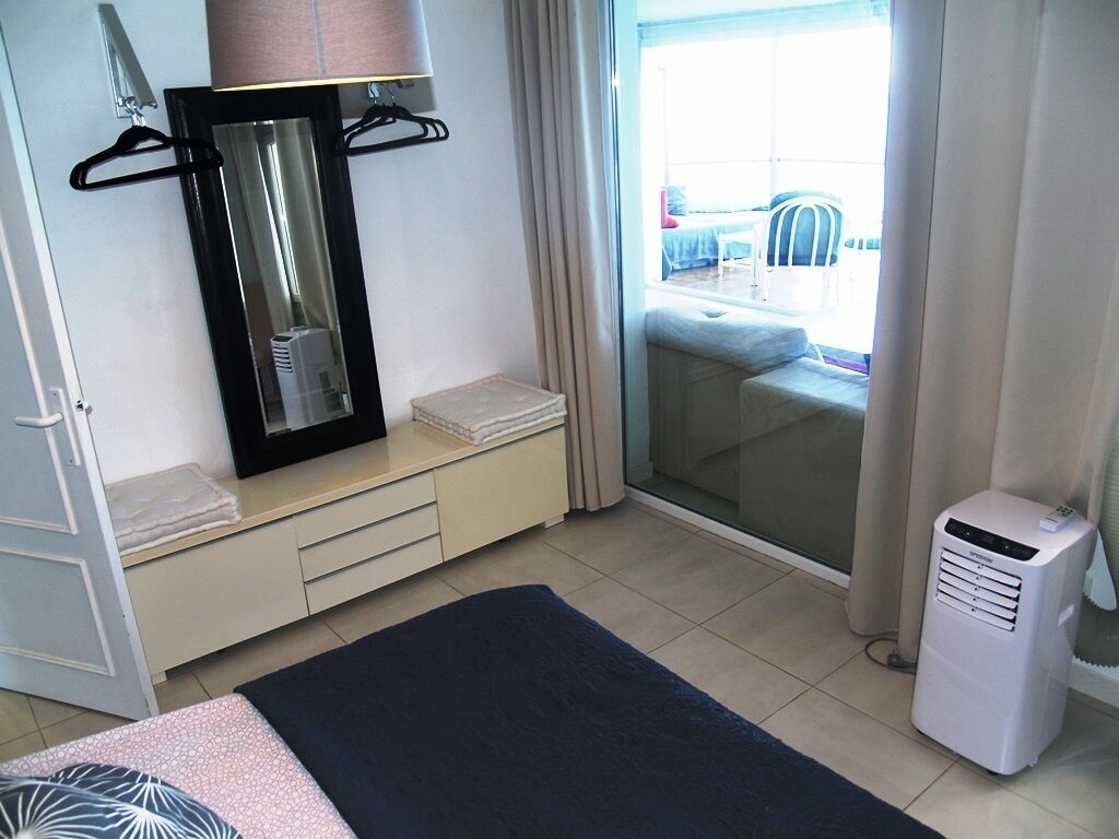Una habitación de hotel con cama, espejo, calefacción y vistas al balcón exterior.