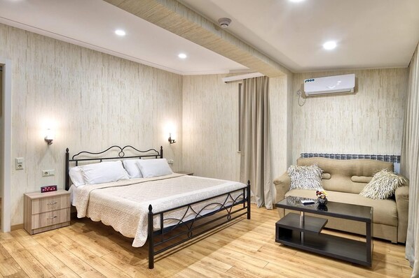 Une chambre à coucher comprenant un lit, une table de chevet, une commode et un canapé avec une table basse.
