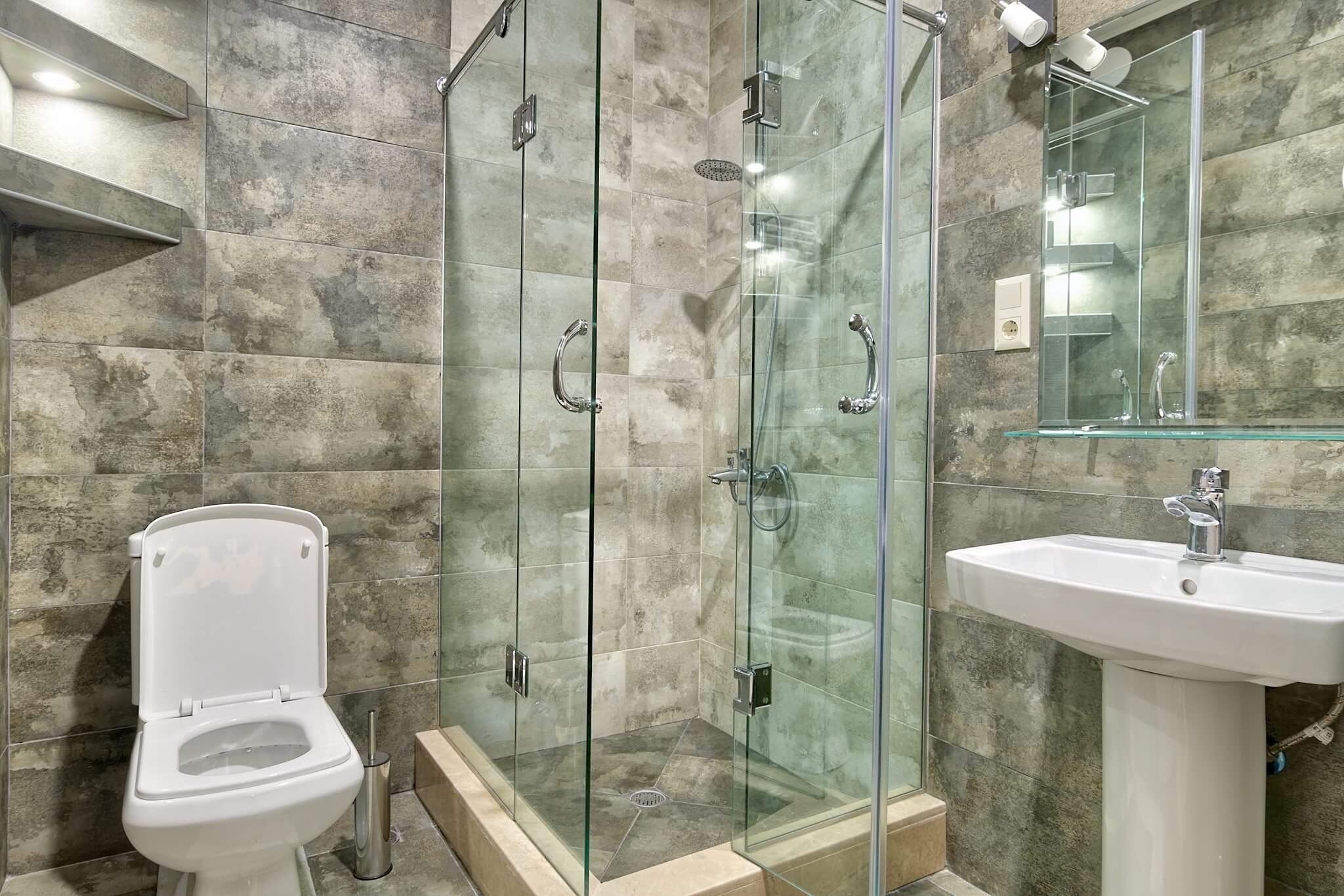 A modern bathroom with a glass-enclosed shower, a white sink, and a toilet.