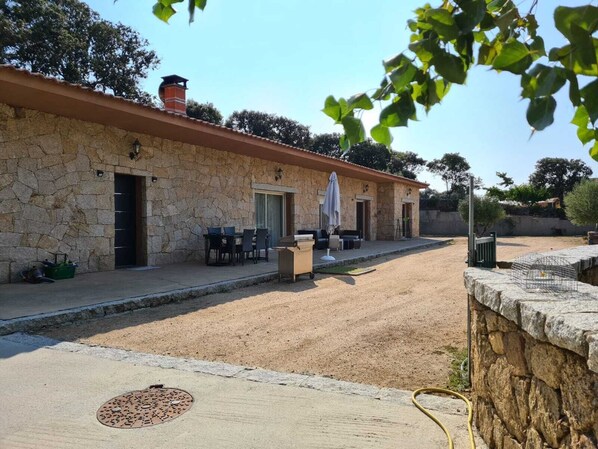 A stone building with a patio area, outdoor seating, and a manhole cover.