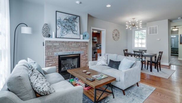 A spacious living room with a fireplace, a dining area, and a kitchen in the background. - 4 Bedroom, 3  Bath  Big Downtown Frederick home, w/ Private Patio &  fire table (Frederick)