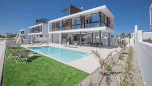 Une maison moderne à deux étages, dotée d’une piscine, d’un espace extérieur aménagé et offrant une vue dégagée sur le ciel.