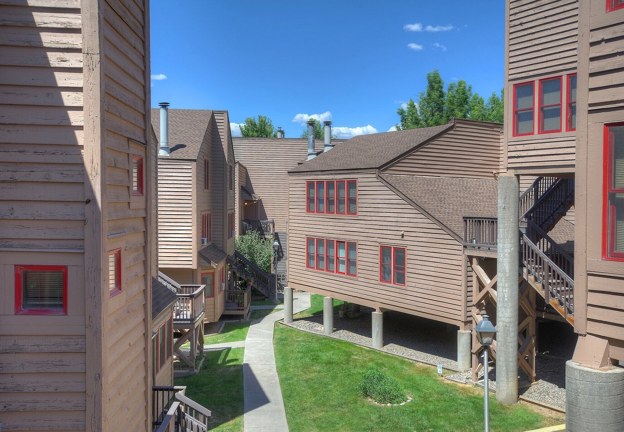 A multi-story building with a central courtyard, wooden exterior, and red-framed windows.