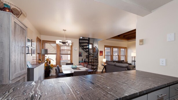A spacious kitchen with a marble countertop, a dining area with a table and chairs, a staircase leading to an upper level, and a living area with a sofa and lamp. - Durango Townhome w/ Pool/Hot Tub | Near FLC, Town, Golf & Trails (Durango)