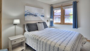A bedroom with a bed, two bedside tables, a wall-mounted lamp, a window with curtains, and a painting above the bed. - Village View Vista | Walk to Town, Pool/Hot Tub - Near FLC, Golf (Durango)