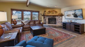 A cozy living room with a fireplace, leather sofas, a coffee table, and a large TV. - Purgatory townhome with Easy Access to Slopes - Views - EV Charger (Durango)