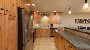 A kitchen with wooden cabinets, stainless steel appliances, a granite countertop, and a hanging light fixture. - Purgatory townhome with Easy Access to Slopes - Views - EV Charger (Durango)